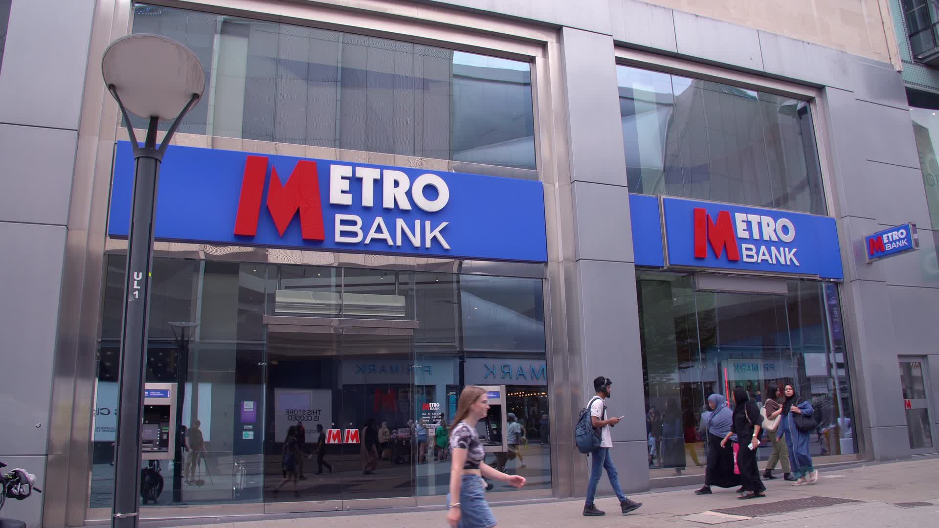 Metro Bank Storefront with Pedestrians on Busy Street
