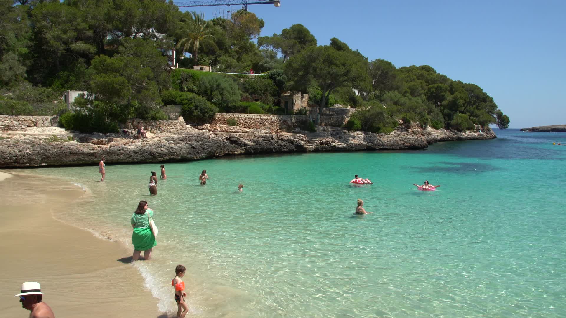Sunny Day at Cala d'Or Beach in Spain with Visitors Enjoying the Water