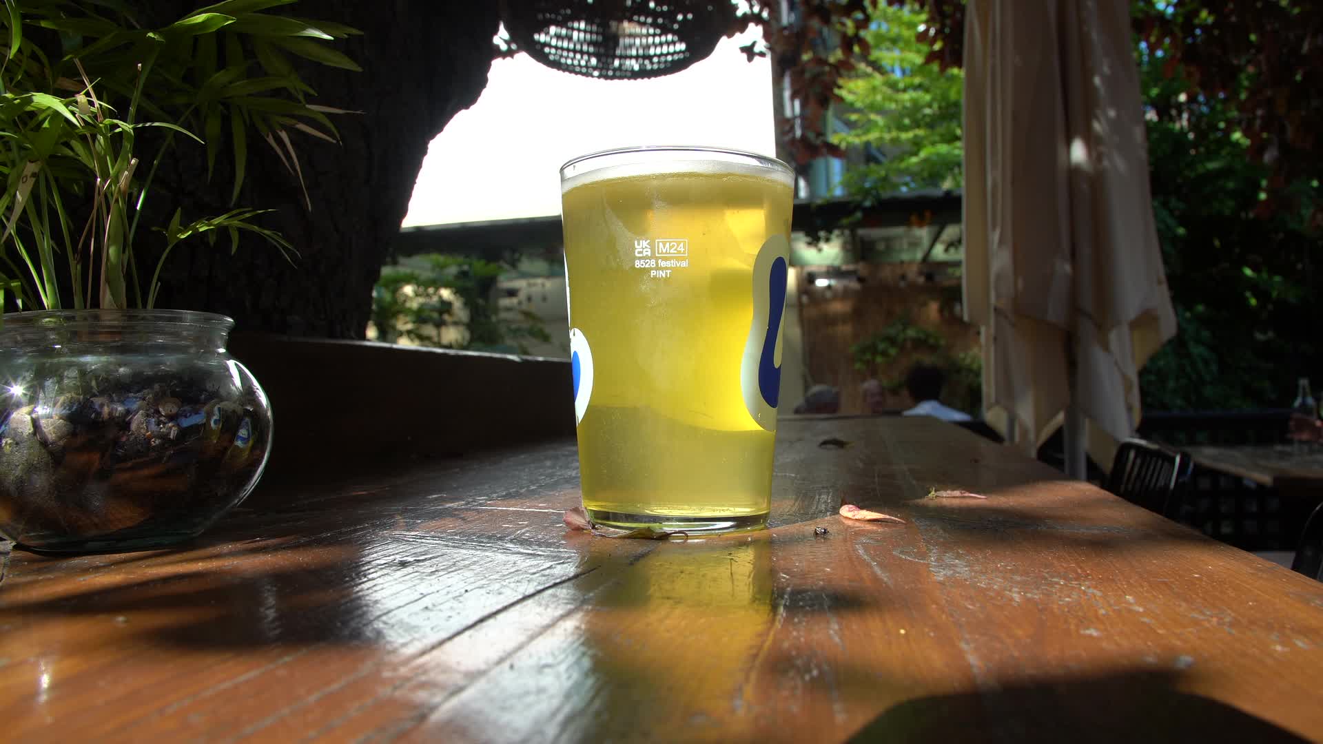 Pint of Beer Being Placed on Outdoor Table in Sunny London Pub Garden
