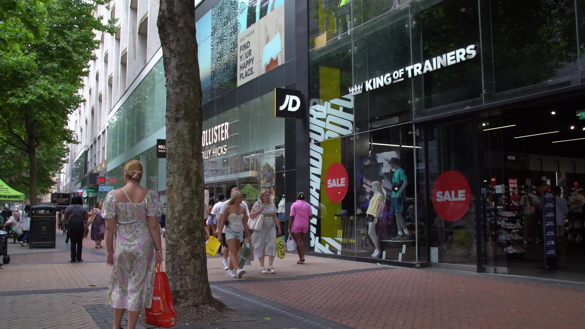 Shoppers at JD Sports Storefront on a Busy Street