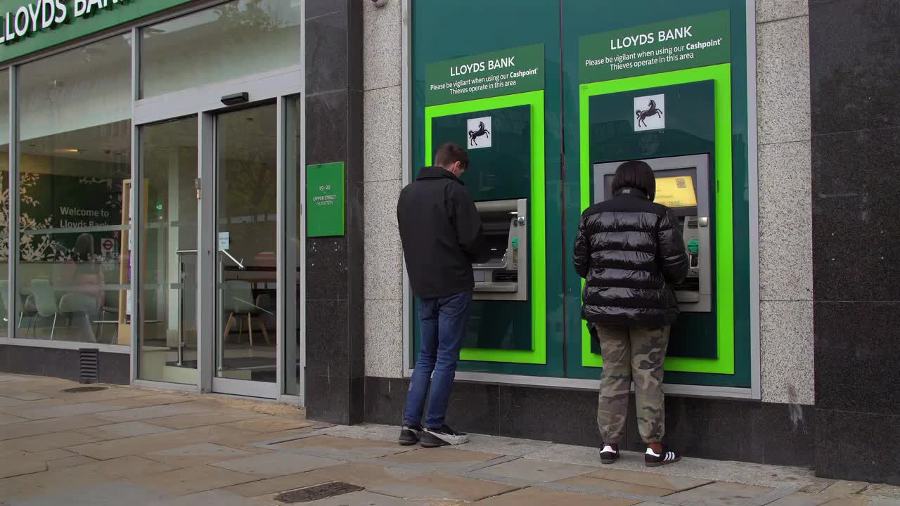 People Using Lloyds Bank ATMs on City Street