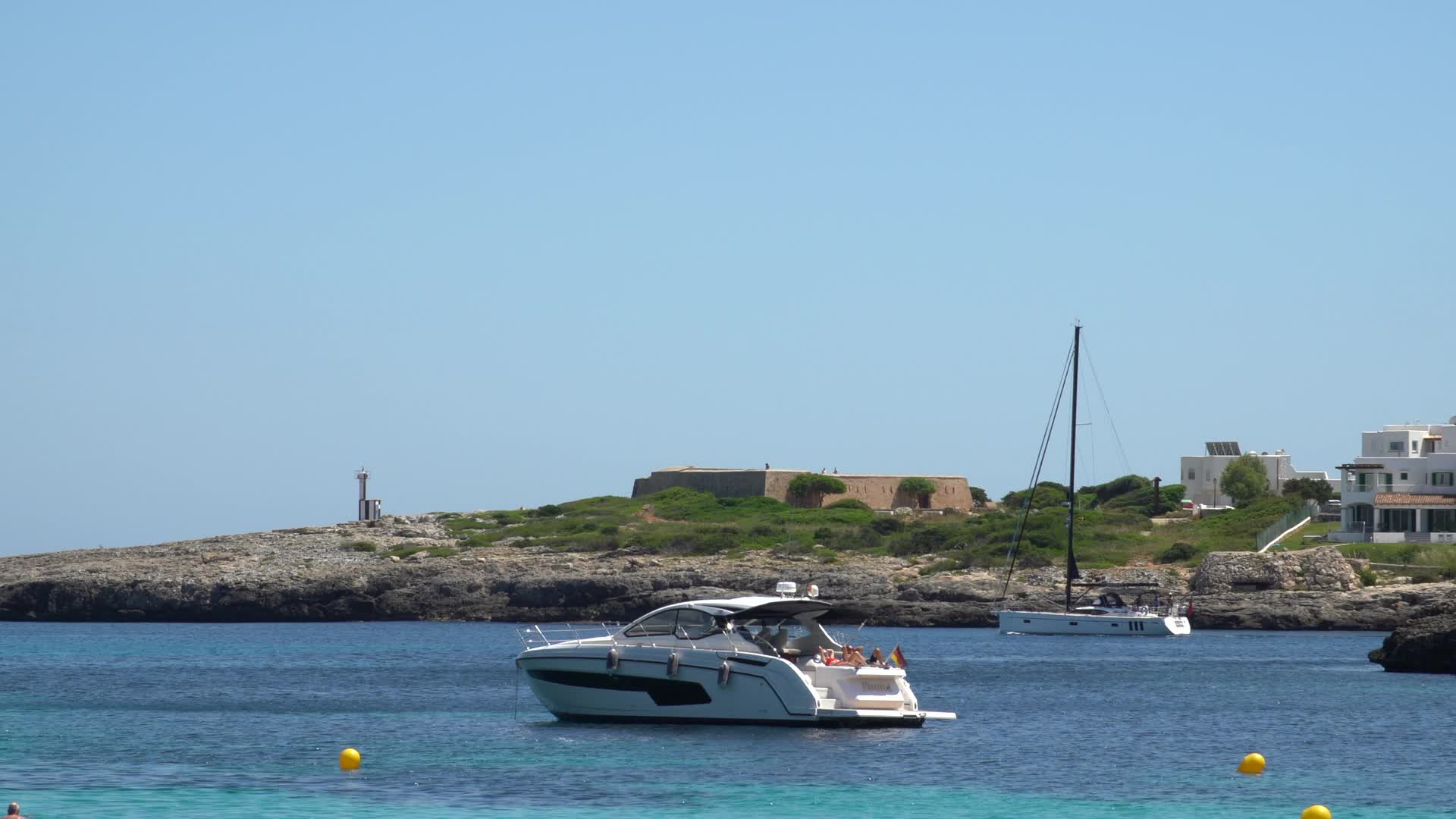 Boats and Distant Lighthouse at Beach in Cala d'Or, Mallorca, Spain