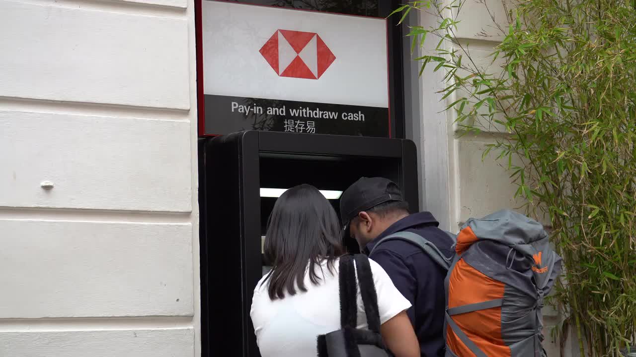People Using HSBC ATM on Urban Street