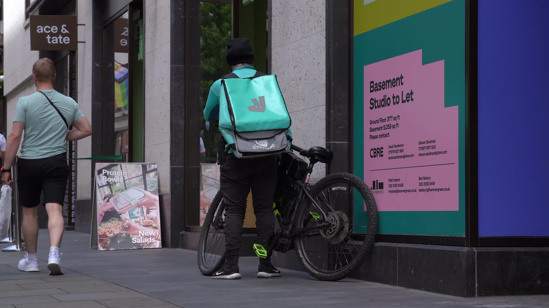 Urban Delivery Cyclist Near Shopfront